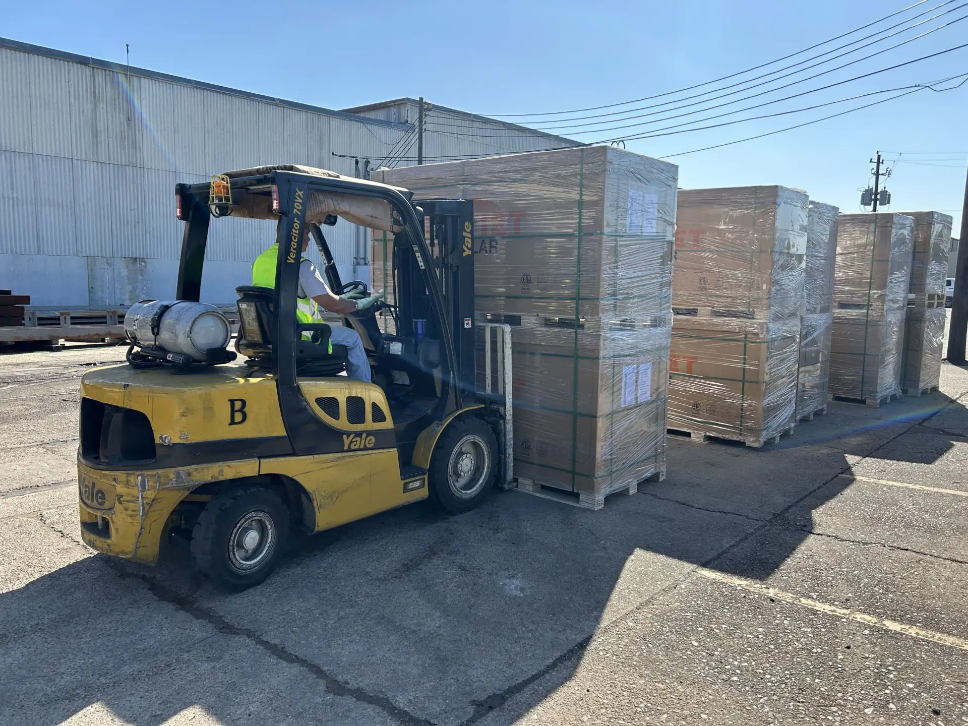 A forklift is parked next to boxes in the parking lot.
